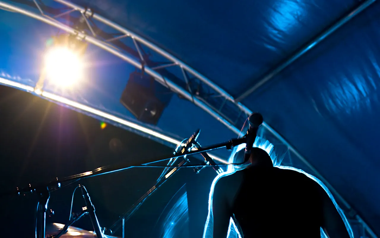 Drummer lit in deep blue stage light.